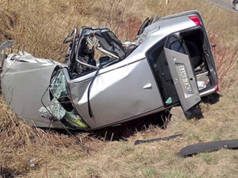 Vehículo volcado en un accidente en un terreno de pasto seco.