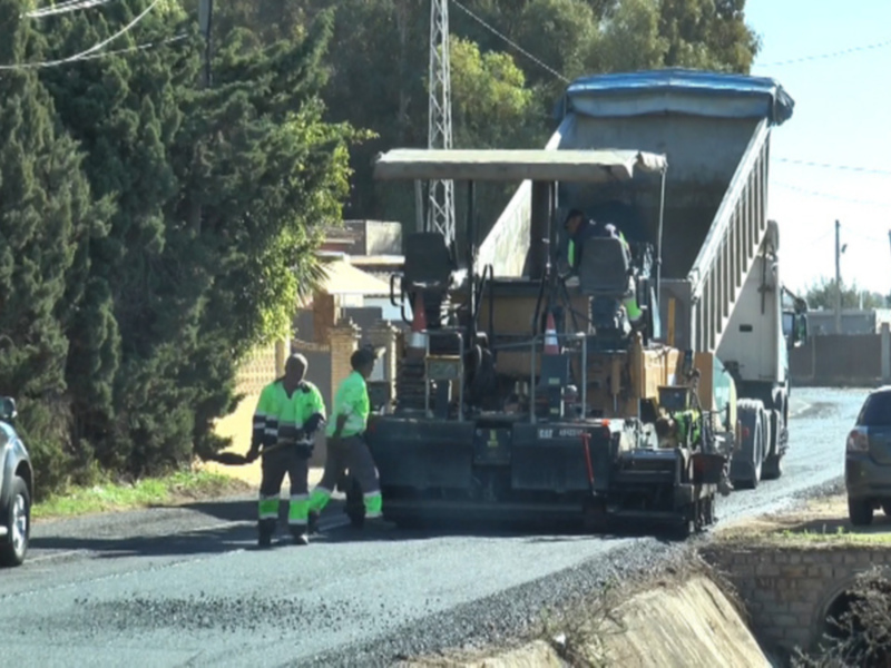 Trabajadores de mantenimiento de carretera asfaltando una vía rural.