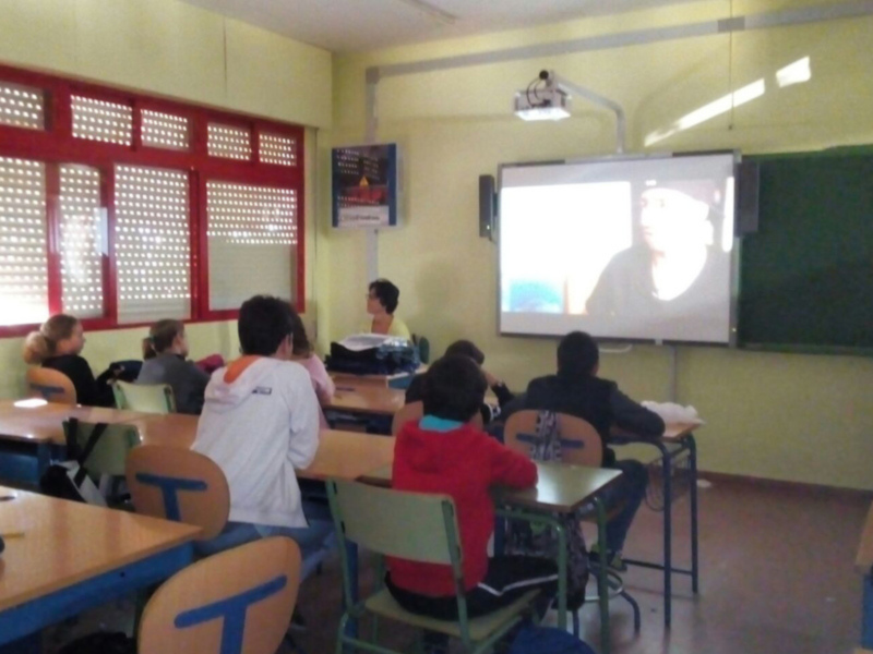 Clase en un aula con proyector y estudiantes observando una presentación.