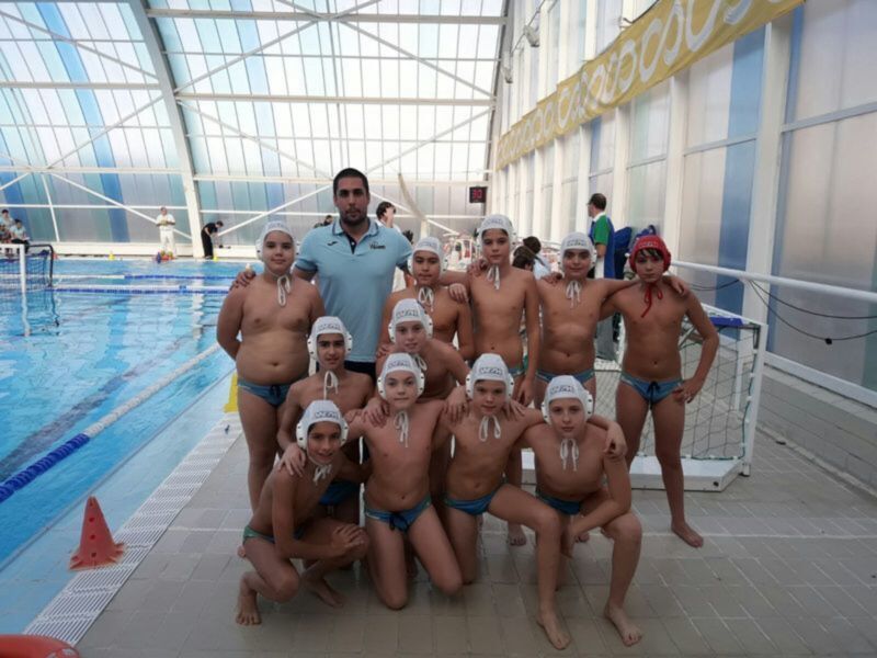 Equipo de waterpolo juvenil posando en la piscina cubierta antes de un partido.