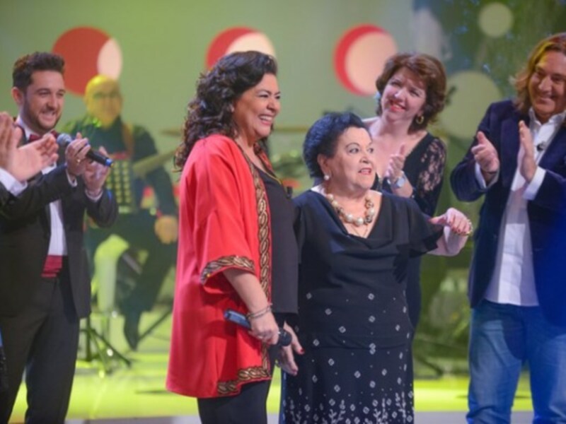 Una escena de una celebración en un escenario con luces brillantes y personas celebrando con aplausos y sonrisas.