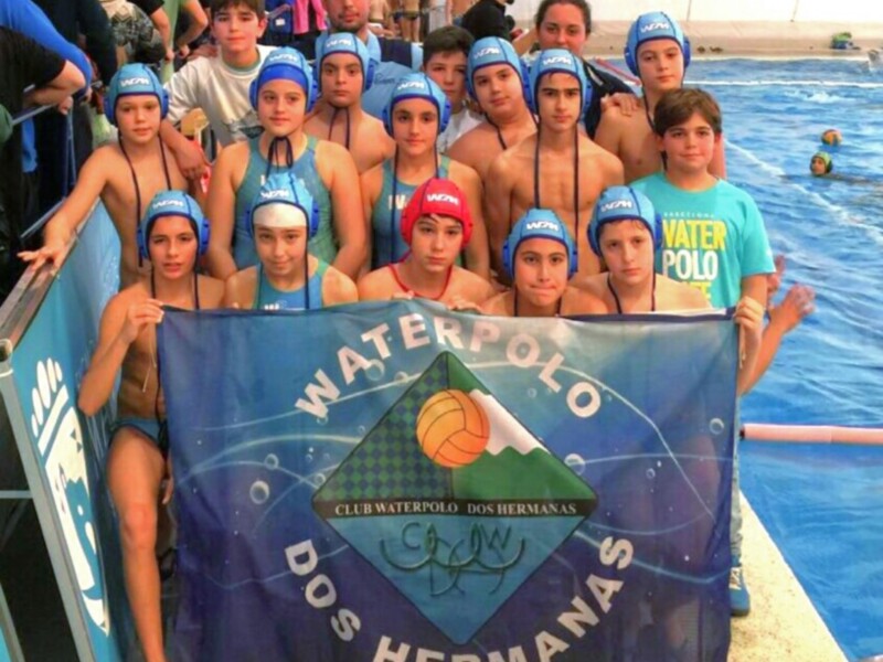Equipo de waterpolo del Club Waterpolo Dos Hermanas posando con su bandera en la piscina.