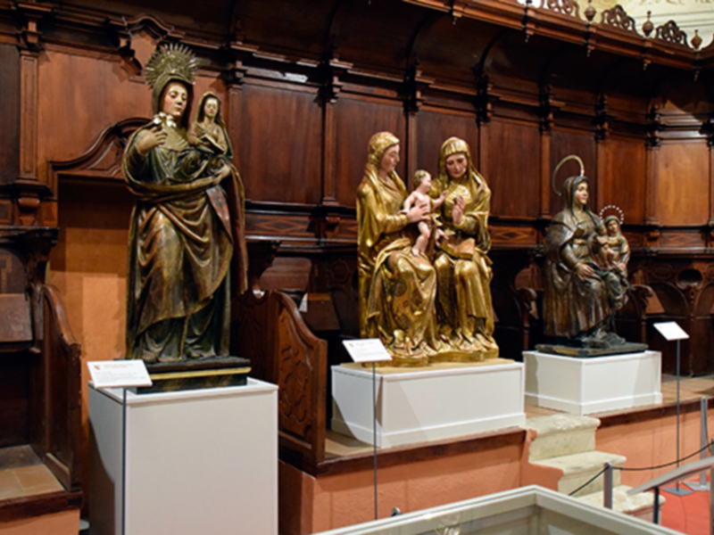Esculturas religiosas en un entorno museístico con madera tallada y paneles ornamentales.