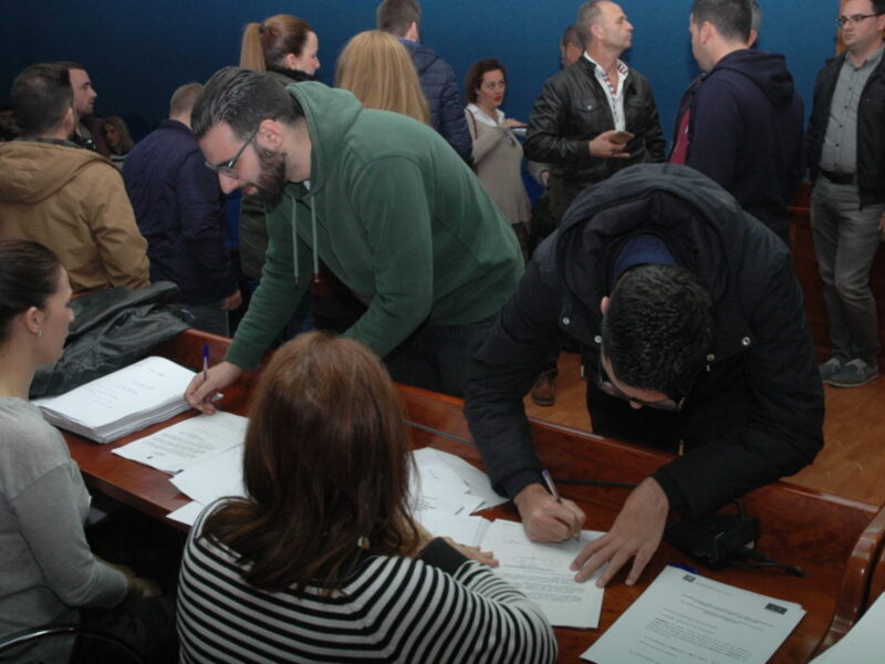 Persona firmando documentos en una reunión o evento formal.