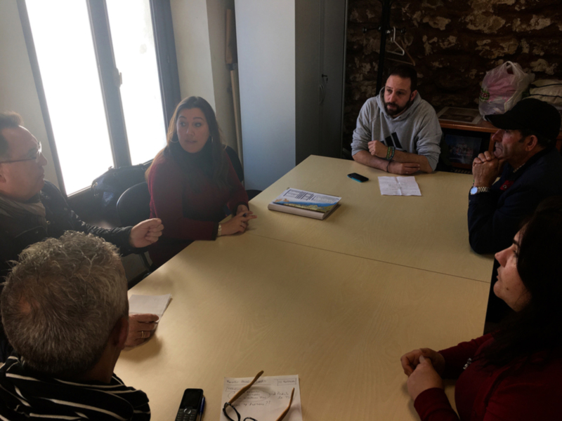 Reunión de trabajo en una mesa con documentos y teléfonos, en un entorno acogedor con paredes de piedra.