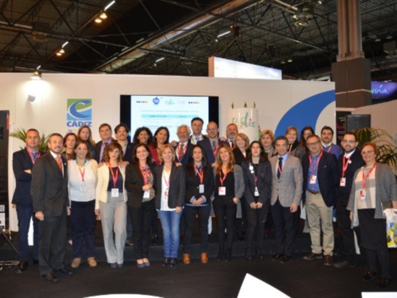 Equipo de profesionales en un evento de Cádiz, posando juntos en un stand bien iluminado.