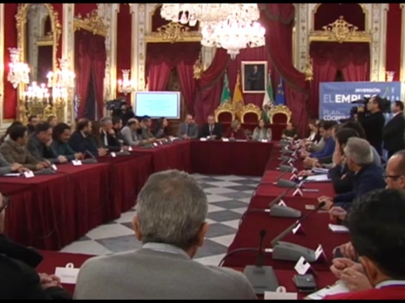 Asamblea de trabajo en una sala de conferencias con decoración elegante y una pantalla de presentación en el centro.