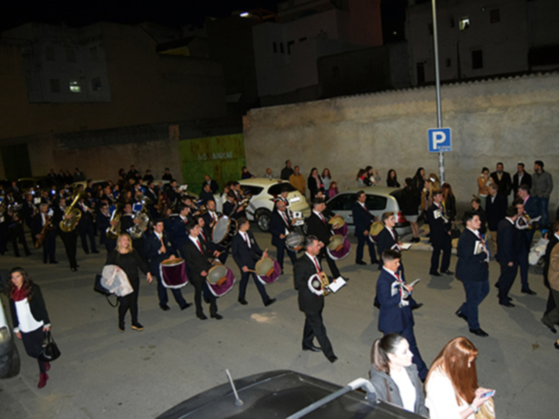 Banda de música desfilando por la noche en una calle urbana.