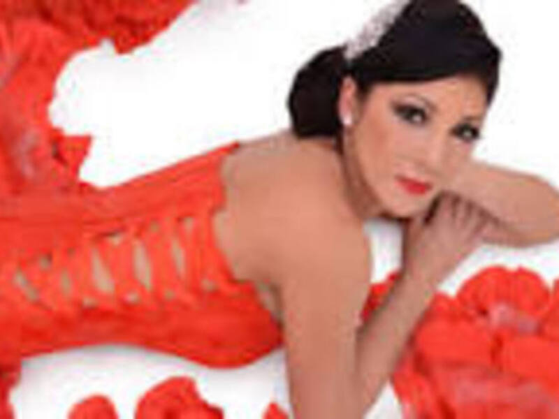 Elegante mujer en vestido rojo con flores rojas en el suelo.