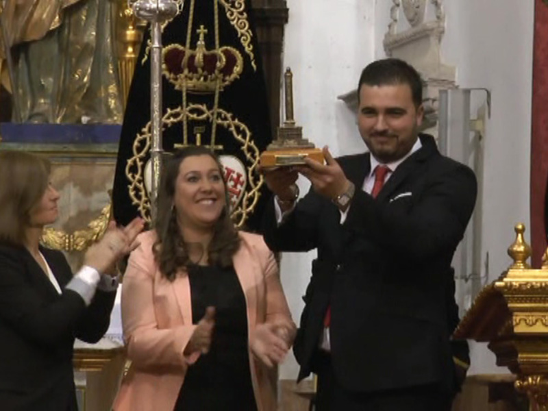 Celebración en una iglesia con tres personas felices, una sosteniendo un trofeo en un ambiente ornamental y religioso.