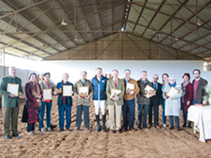 Gruppo di persone in piedi in un hangar, ciascuno con un premio in mano.
