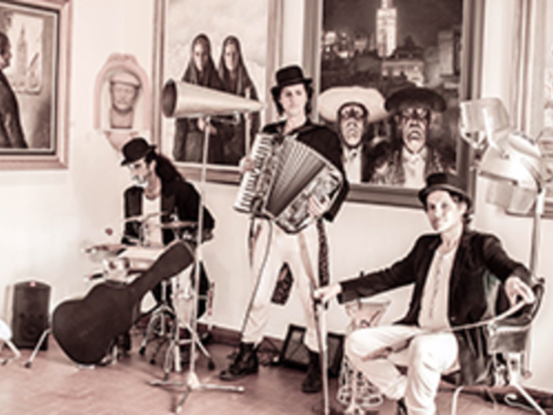 Un grupo de músicos en un estudio de grabación, tocando instrumentos y posando para la cámara. El ambiente es casual y creativo, con una mezcla de instrumentos clásicos y modernos. La imagen transmite un sentido de comunidad y pasión por la música.