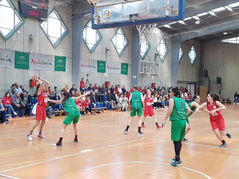 Juego de baloncesto femenino en un pabellón deportivo con público en la grada.