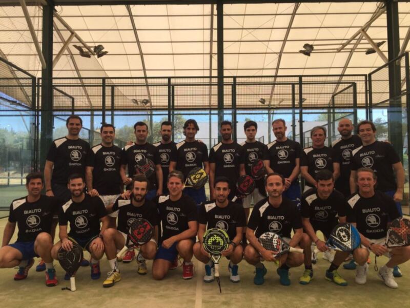 Equipo de padel posando en una cancha de pádel, todos con camisetas negras con logotipos de Skoda y Biauto. Los jugadores sostienen raquetas de pádel de diferentes marcas.