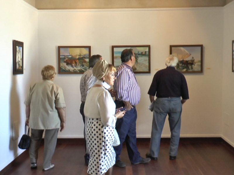 Visitantes observando pinturas en una exposición de arte en un museo.