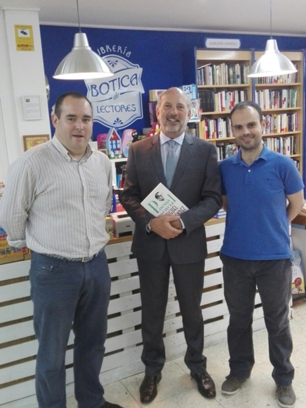 Tres personas posan juntas en una librería, con uno de ellos sosteniendo un libro y el letrero 'Librería Botica de Lectores' en el fondo.