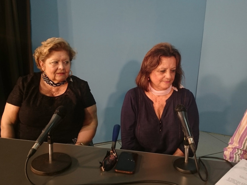 Tres personas sentadas en una mesa con micrófonos, posiblemente en una conferencia o reunión formal.