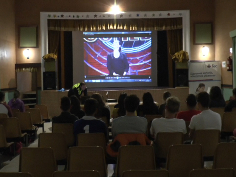 Auditorio lleno de estudiantes viendo una presentación en pantalla grande.