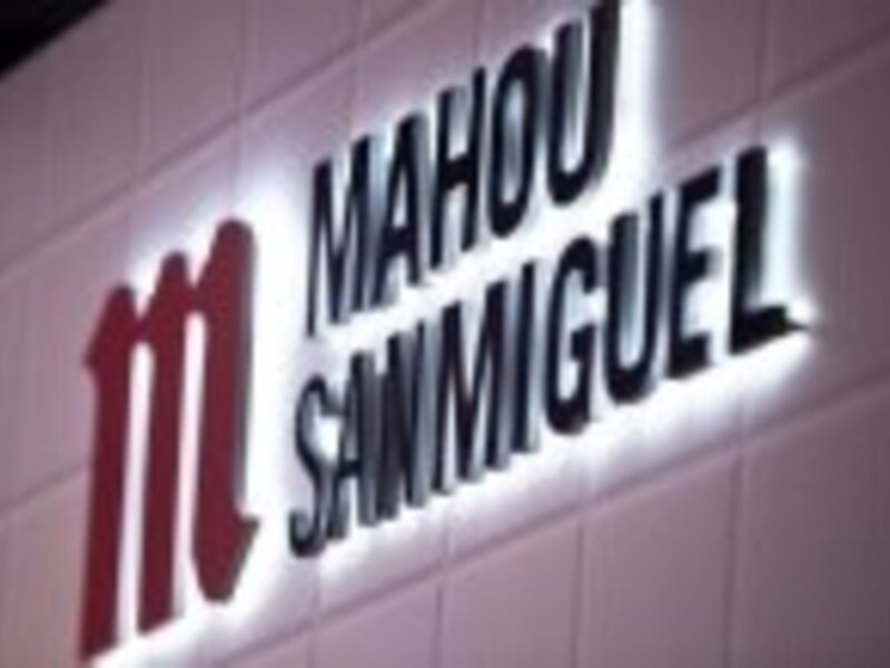 Específico de la empresa Mahou San Miguel en una pared de ladrillo. El logo está iluminado y destaca contra el fondo de la pared.