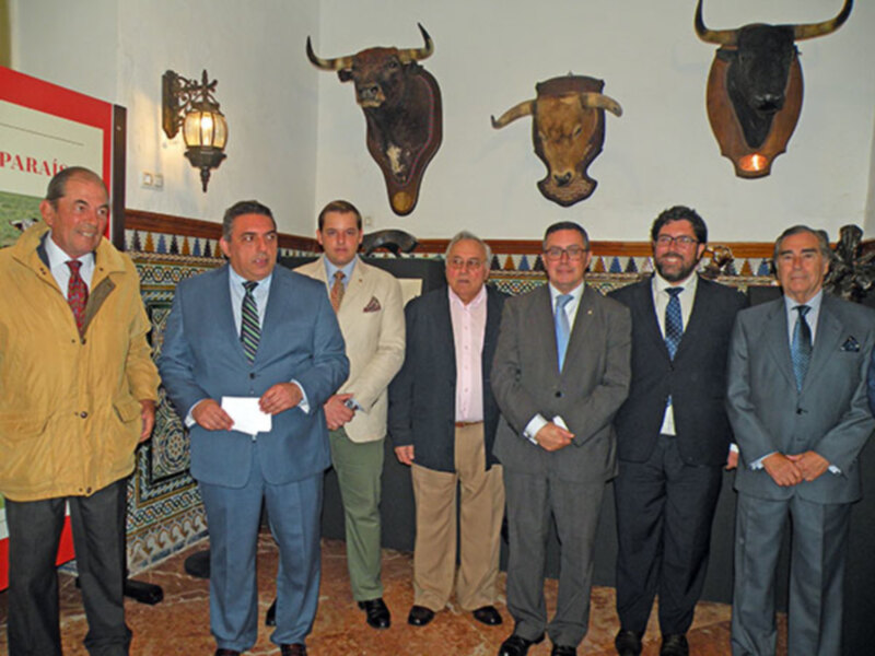 Grupo de hombres en trajes posando en una sala decorada con cabezas de toros.