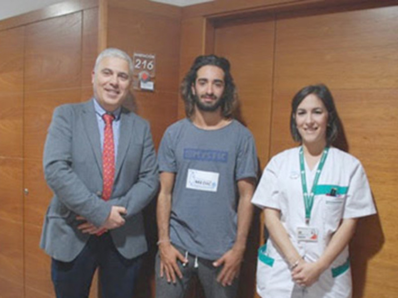 Tres personas sonrientes en una oficina, uno en traje, otro en camiseta y el tercero en uniforme de enfermería.