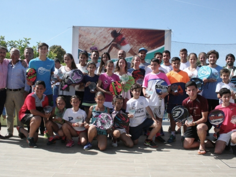 Equipo de padel infantil y adultos celebrando juntos en un evento al aire libre.
