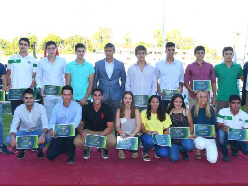 Celebración de graduación con jóvenes estudiantes y autoridades recibiendo diplomas en un evento al aire libre.