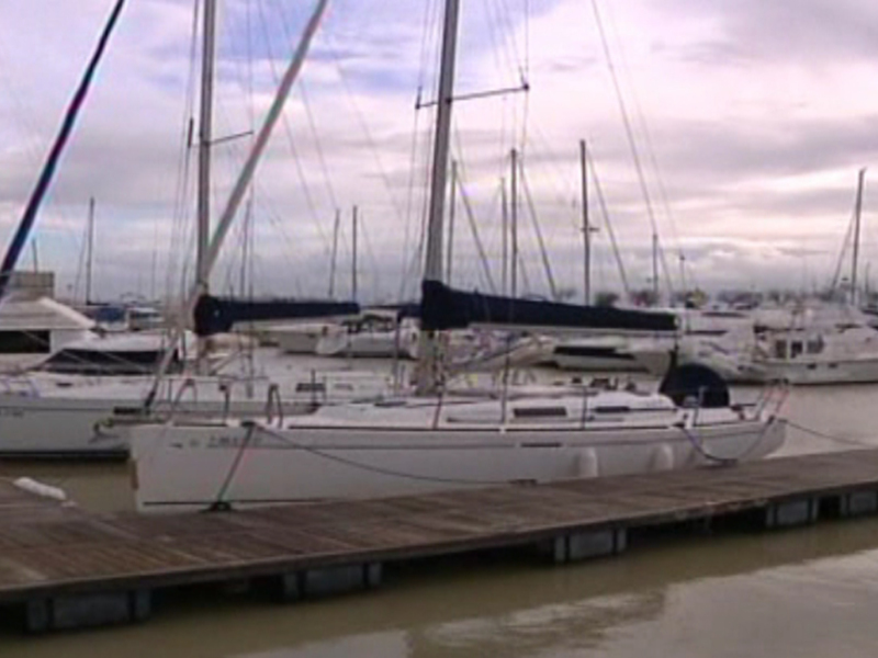 Barcos anclados en un muelle de un puerto con un cielo nublado en el fondo.