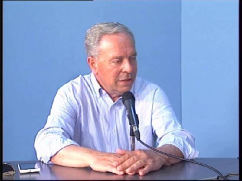 Persona hablando en un micrófono durante una reunión o conferencia.