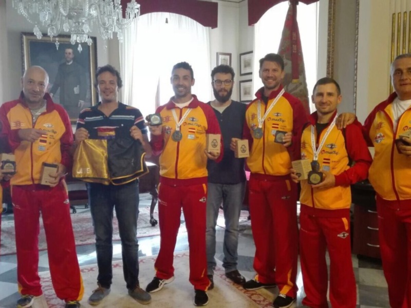 Equipo de atletas celebrando con medallas y trofeos en un ambiente formal.