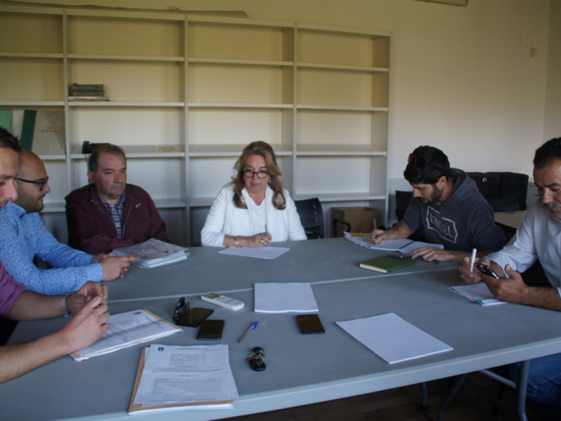 Una reunión de trabajo en una oficina con personas sentadas alrededor de una mesa, utilizando dispositivos electrónicos y documentos para la colaboración.