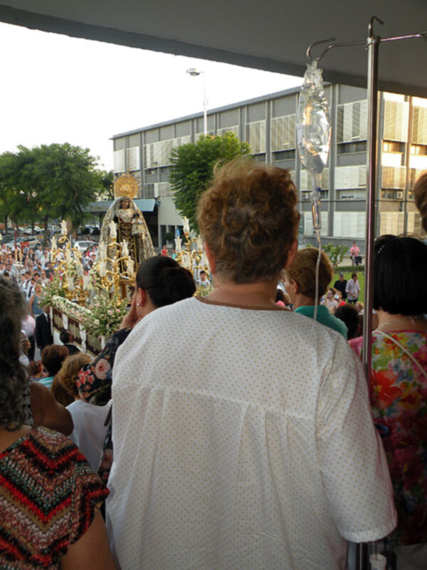 Procesión religiosa con la imagen de la Virgen María en un carro tirado por mujeres, rodeada de fieles en una ciudad.