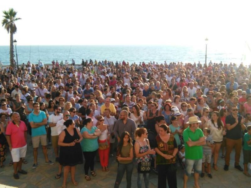 Gran concurrencia en un evento al aire libre junto al mar.