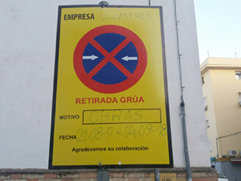 Señal amarilla con símbolo de prohibición de estacionamiento y texto indicando obras de empresa Ullastres del 21-08-17 al 04-09-18.