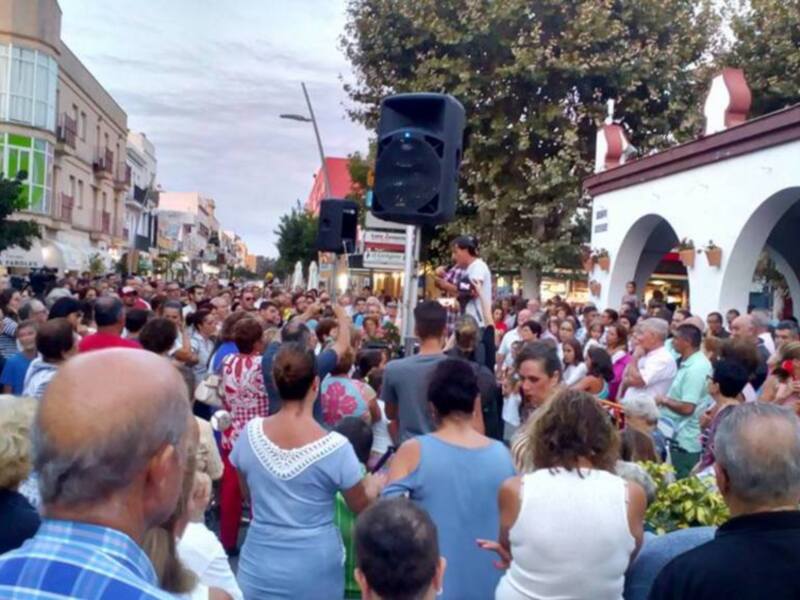 Gran concurrencia en una calle urbana durante un evento público, con gente disfrutando y un sistema de sonido portátil en el centro.
