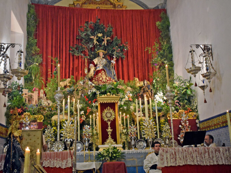 Altar ornado con flores, velas y estatuas religiosas en un ambiente eclesiástico.