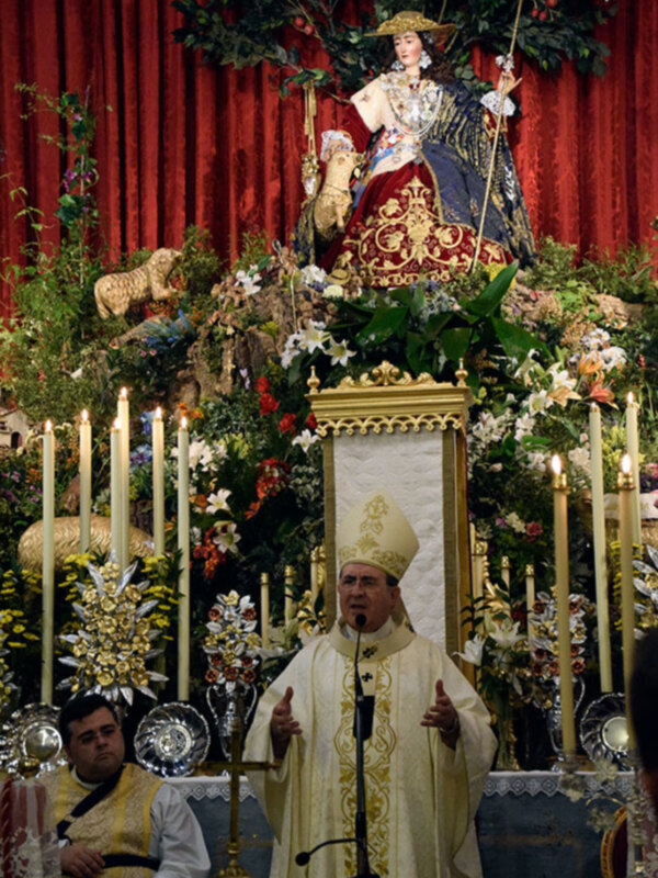 Celebración religiosa con altares adornados y un sacerdote oficiando una ceremonia.