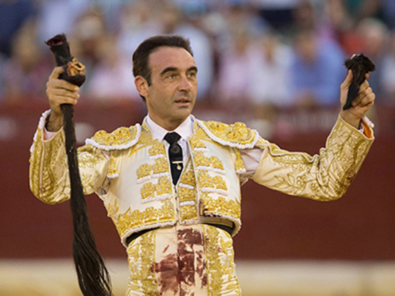 Un torero en traje de luces celebra con un palo de banderillas en una corrida de toros.