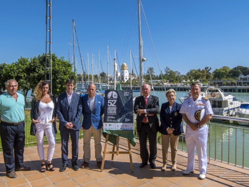 Celebración del 52º Ascenso a Vela del Puerto de Huelva, con autoridades y representantes frente al puerto y veleros en el fondo.