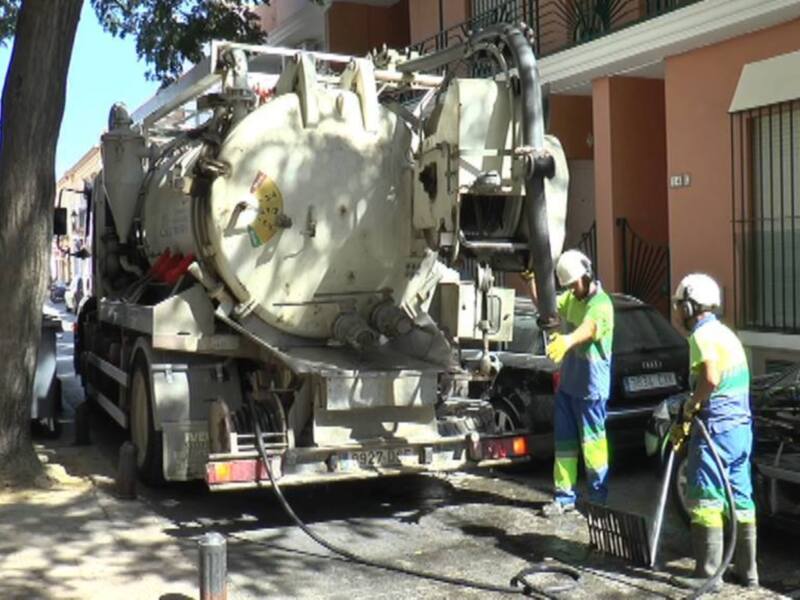 Trabajadores realizando tareas de limpieza con un camión de succión de alcantarillado en una calle urbana.