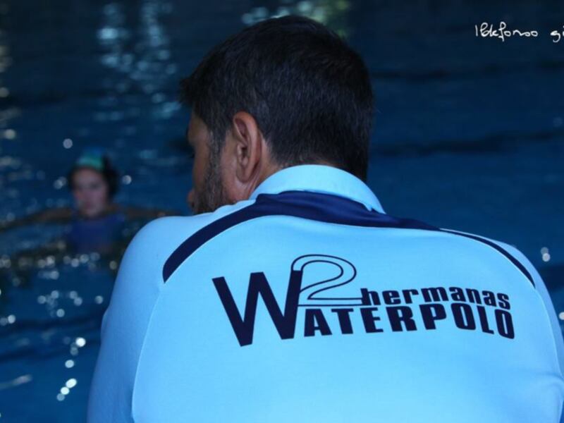 Entrenador de waterpolo observando a sus jugadores en la piscina.