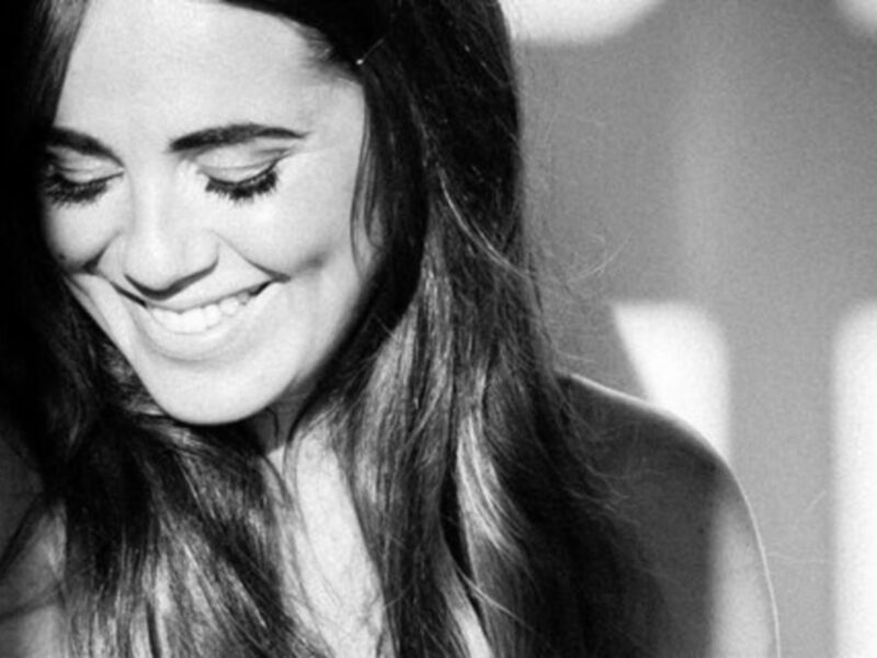 Una mujer sonriendo mientras mira una pantalla digital.