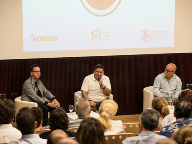 Tres hombres en un panel discutiendo en un evento de Heineken, patrocinado por el Ayuntamiento de Córdoba.
