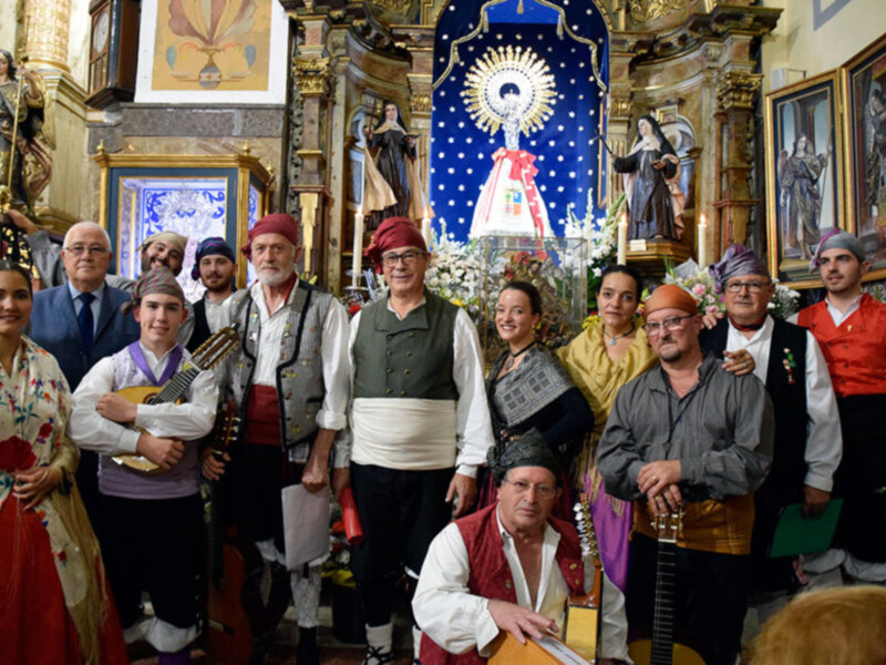 Celebración religiosa en una iglesia con fieles vestidos tradicionalmente y músicos tocando instrumentos.