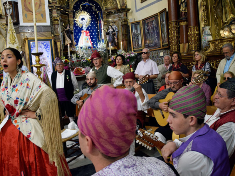Fiesta tradicional en una iglesia con músicos tocando y una mujer en traje regional cantando.
