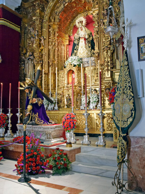 Altar ornado con estatuas doradas y flores rojas en una iglesia católica.
