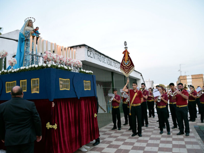Procesión religiosa con una imagen de la Virgen y un grupo de músicos tocando instrumentos.