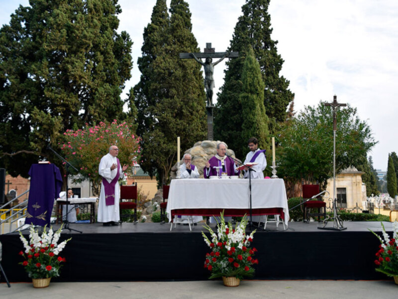 Celebración religiosa con sacerdotes en un altar al aire libre, rodeados de árboles y flores.