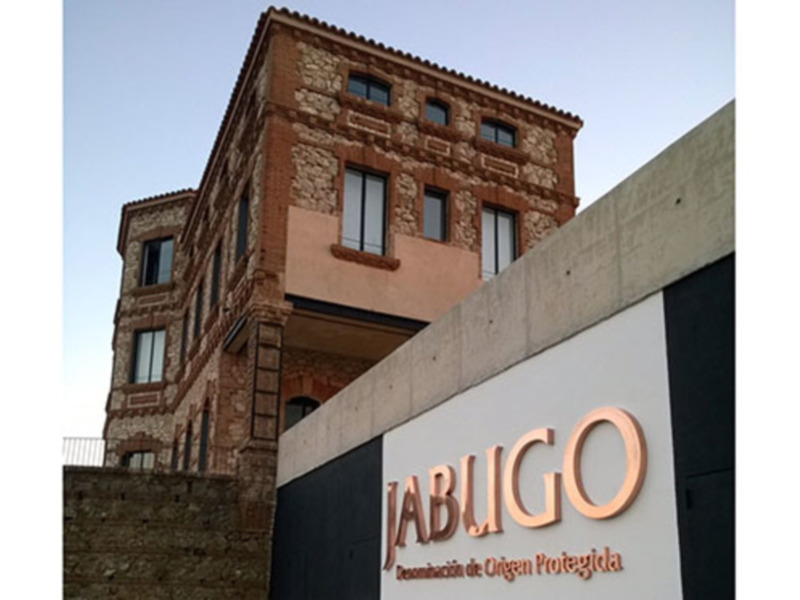 Fachada de un edificio con letras doradas que dicen 'JABUGO' en una zona protegida de la ciudad.