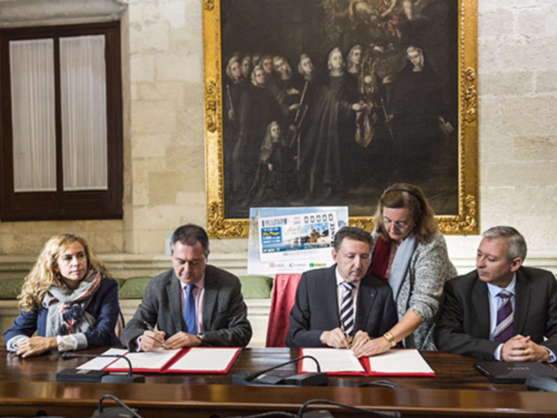 Reunión de firma de documentos en un entorno formal con pintura histórica en el fondo.